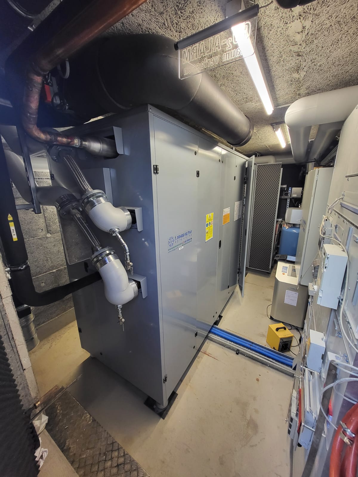 Innenaufgestellte Anlagentechnik der CO₂-Wärmepumpe mit Leitungsanschlüssen und kompakter Einbindung in den Heizungsraum