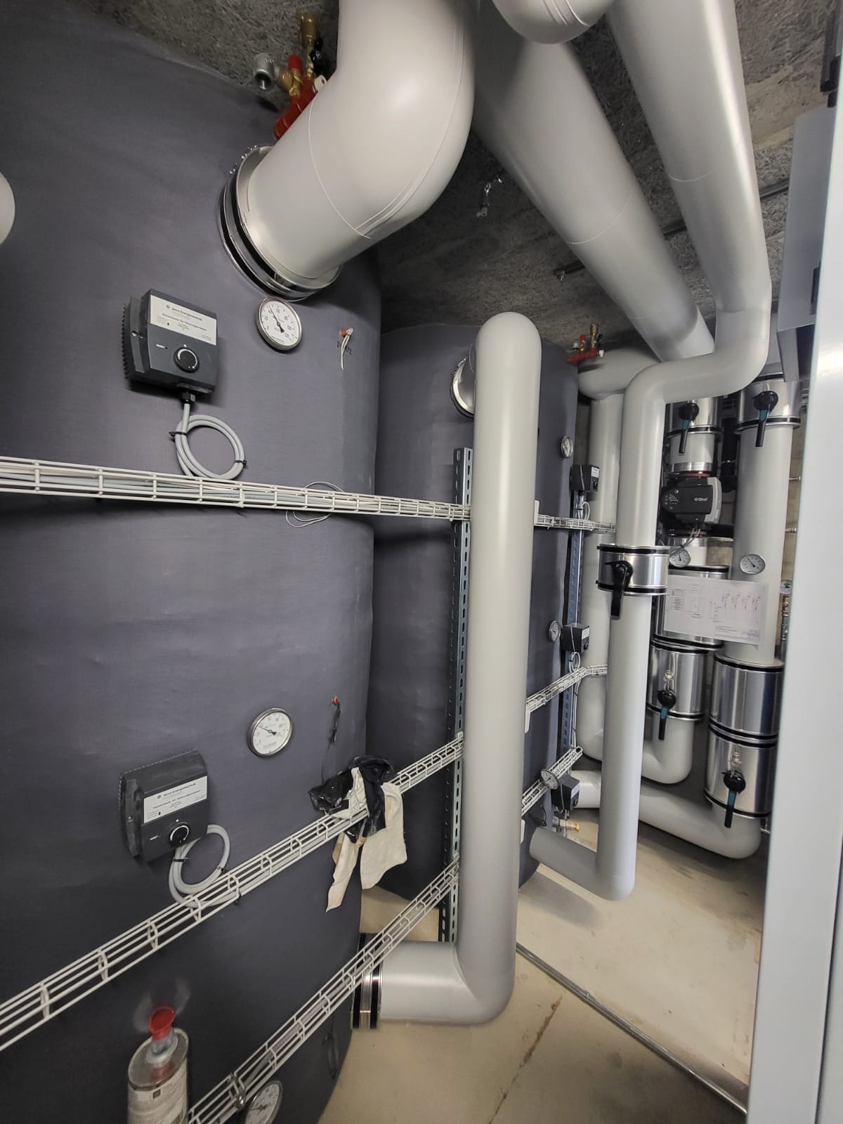 Technikinstallation im Heizungsraum mit gedämmten Leitungen, Wärmespeicher und Komponenten der CO₂-Wärmepumpenanlage.