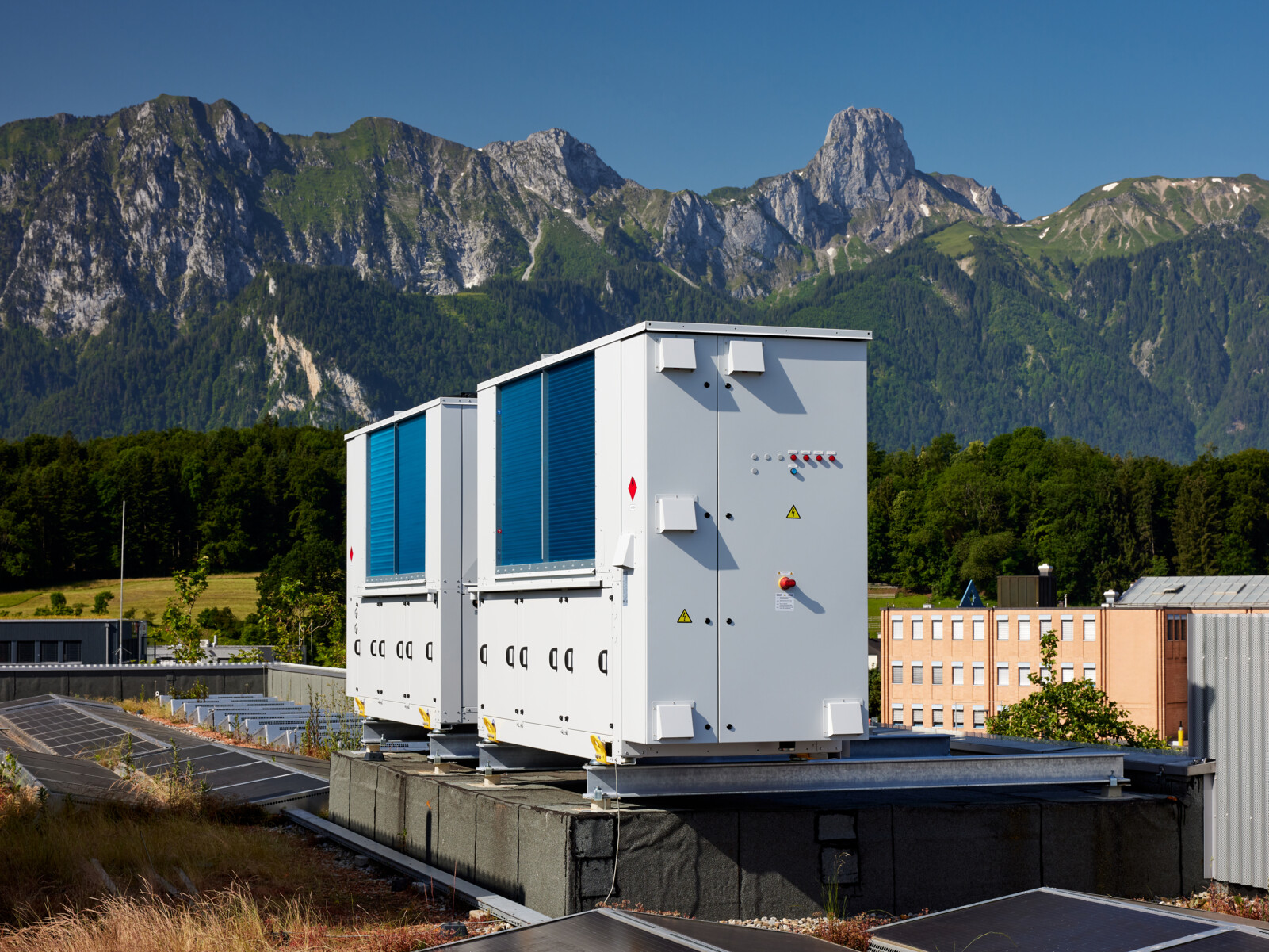 Weiss blaue Propan Wärmepumpe auf Flachdach vor atemberaubender Bergkulisse - Propan Wärmepumpe Zaugg AG
